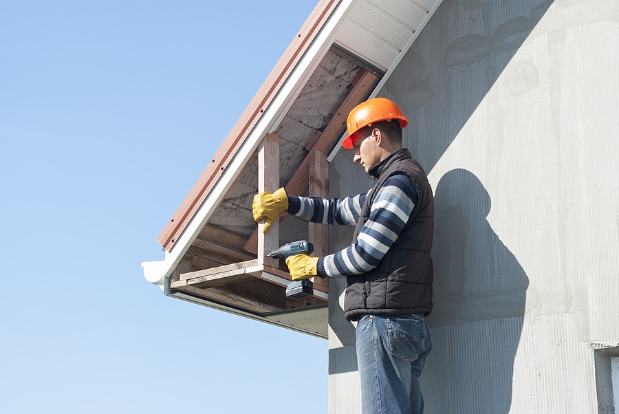 Construction worker mounts a soffit on the roof eaves.